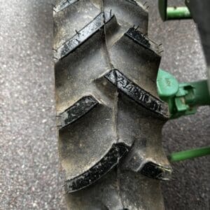 IMG_1387 - Montana Auctions by Kevin Hill Close-up of a large off-road tractor tire with deep chevron tread on a green farm implement.