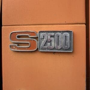 IMG_6532 - Montana Auctions by Kevin Hill Orange vehicle door featuring a chrome 'S 2500' badge as a close-up detail.