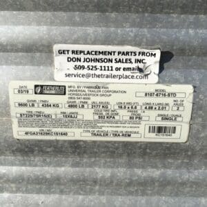 Screenshot - Montana Auctions by Kevin Hill Close-up of a trailer identification sticker on a weathered metal surface with Don Johnson Sales contact info to order parts.