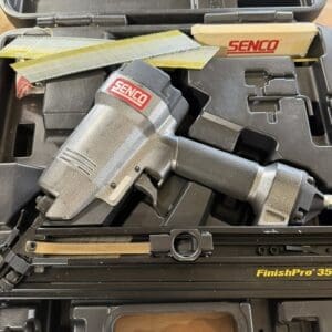 Open tool case containing a Senco FinishPro 35 nail gun, a box labeled Senco, and loose metal staple strips inside.