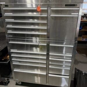 Stainless steel HammerHead tool cabinet on casters in a workshop, with many labeled drawers and a central tall drawer on the right.