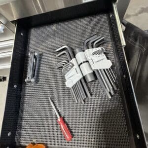 Open tool drawer with hex keys and Allan wrenches, a red-handled screwdriver, and a label that reads 'CHISELS AND PUNCHES'.