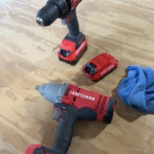 Three Craftsman cordless drills on a wooden workbench with a blue towel nearby.