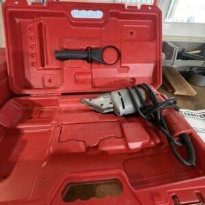 Red plastic toolbox open with a cordless reciprocating saw and a separate hand tool in the lid compartment.