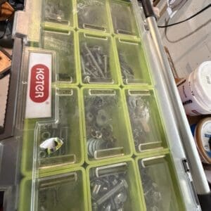 Plastic toolbox with yellow-green divided compartments filled with screws, nuts, and bolts; Keter logo on side.