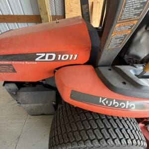 Kubota ZD1011 zero-turn mower with a large rear tire, stored in a shed.