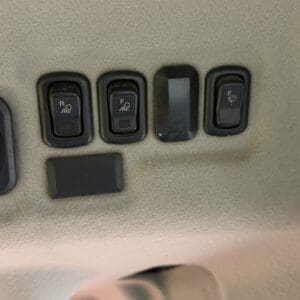 Overhead panel in a car with three rocker switches (two labeled R and F with fog icons) and a blank switch on a beige headliner.
