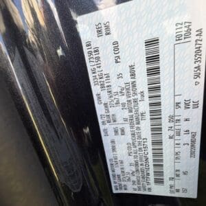 Vehicle information label on a door jamb showing VIN, tire and weight specs.