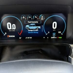 Car dashboard with 0.0 RPM on left, 0 mph on right; center shows Fuel Economy with an image of a blue pickup and 'Electric Driving' text, indicating electric mode.