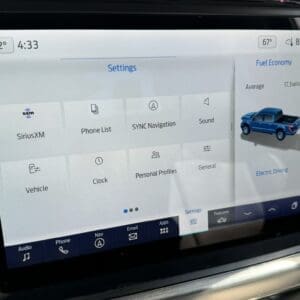 Car infotainment Settings screen with tiles: SiriusXM, Phone List, SYNC Navigation, Sound, Vehicle, Clock, Personal Profiles, General, and a bottom navigation bar