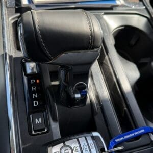 Close-up of an automatic gear shift in a car with PRND indicators and a key fob on the console.