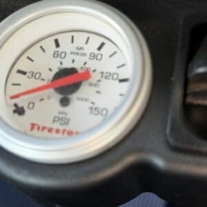 Close-up of a Firestone tire pressure gauge showing about 25 PSI on a white dial with a red needle point]. But more precisely: The gauge reads around 25 PSI.