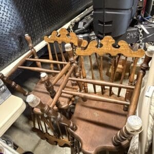 Group of wooden dining chairs with turned spindles stacked in a dim storage area.