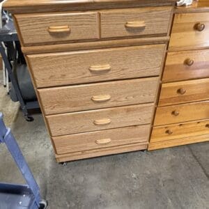 Oak wood dresser with six large drawers and two small top drawers on casters in a workshop.