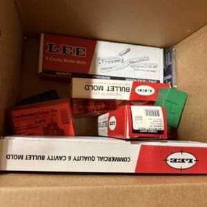 Open cardboard box with LEE bullet mold packaging and red/white boxes inside, showing the LEE logo and '6 Cavity Bullet Mold' text