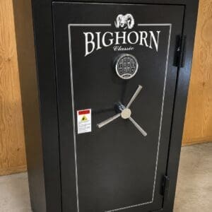 Large black Bighorn Classic safe with a keypad lock and cross-shaped handle in a wood-paneled room