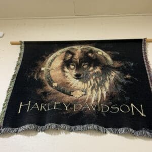 Harley-Davidson banner hanging on a wall with a wolf head inside a circular ring and the Harley‑Davidson lettering beneath it.