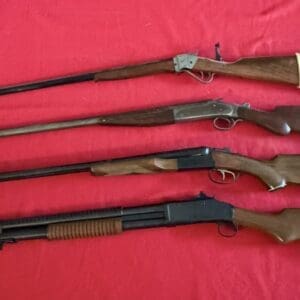 Four rifles with wooden stocks laid in a row on a red fabric surface, displaying varying barrel lengths and receivers.
