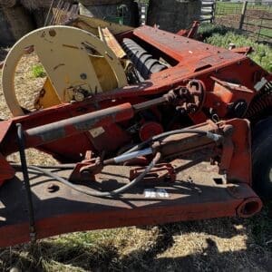 LOT 1 4 - Montana Auctions by Kevin Hill Red, rusted agricultural implement with a large beige reel and exposed gears parked in a grassy yard.