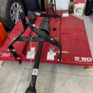 LOT 9 1 - Montana Auctions by Kevin Hill Red flatbed utility trailer with a black hitch assembly and safety chain in a garage setting.