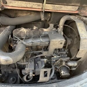 1 4 - Montana Auctions by Kevin Hill Under-hood view of a dusty diesel engine with hoses, belts, and a cooling fan visible, showing signs of dust and grime buildup
