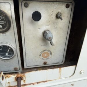 10 2 - Montana Auctions by Kevin Hill Old industrial control panel with a black push button, a small toggle, and a gray lever labeled Run/Hold/Start; rusty metal and Gardner-Denver logo nearby.