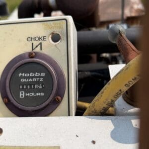 12 2 - Montana Auctions by Kevin Hill Close-up of a weathered control panel with 'PULL WHEN STARTING' and 'CHOKE' labels, showing a round dial and a rusty lever edge.