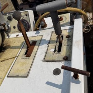 12 3 - Montana Auctions by Kevin Hill Weathered industrial control panel with rusted levers labeled Disengage and Reverse, featuring a gray T-bar and yellow cable.