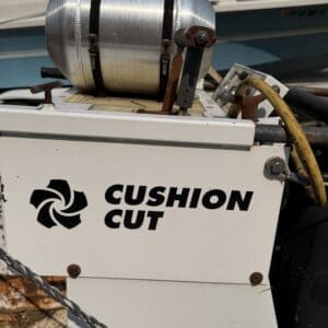 12 5 - Montana Auctions by Kevin Hill White control box labeled 'CUSHION CUT' with a metal canister on top and rusted hardware, beside a boat.