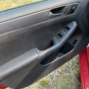 13 7 - Montana Auctions by Kevin Hill Car door interior panel with a gray armrest and window control buttons on the armrest area, and a door handle visible near the top window edge.
