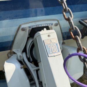 16 2 - Montana Auctions by Kevin Hill White Volvo Penta 230 outboard motor mounted on a boat, with a rusted chain hanging nearby.