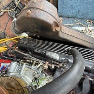 16 8 - Montana Auctions by Kevin Hill Rusty exhaust elbow and marine engine in a boat engine bay, with Volvo Penta 290A label and worn hoses nearby