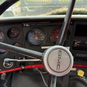 18 7 - Montana Auctions by Kevin Hill Vintage GMC vehicle dashboard with a large steering wheel and round gauge cluster visible behind it