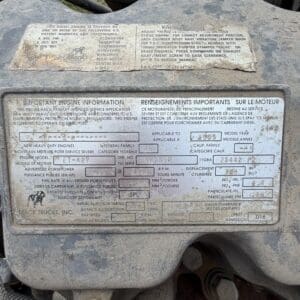 19 3 - Montana Auctions by Kevin Hill Dusty diesel engine data plate with model, serial number, RPM, and fuel specs in a heavy-duty engine compartment.