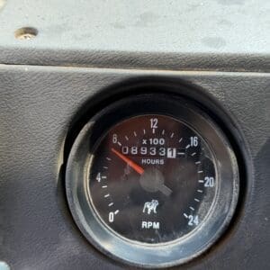 19 7 - Montana Auctions by Kevin Hill Close-up of a vehicle dashboard gauge showing RPM (x100) and an hours meter reading 89,331 hours, with a red needle around the low range.