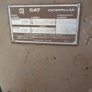 2 5 - Montana Auctions by Kevin Hill Metal nameplate on a brown machine showing Caterpillar model and serial information, with numbers like 206, 3G00152, 7V120 and 4.236 engine details visible but worn.
