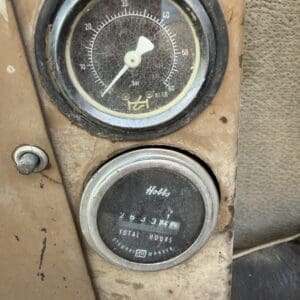 2 6 - Montana Auctions by Kevin Hill Old dusty vehicle dashboard with a round pressure gauge (0–60 bar) and a 'Hobbs' total hours meter on a rusty panel.
