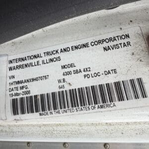 22 2 - Montana Auctions by Kevin Hill Vehicle identification label on a dirty white surface showing the manufacturer, location, model (4300 SBA 4X2), VIN, date of manufacture (19-Mar-2008), and a barcode; made in the United States.