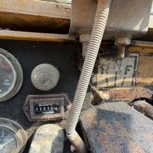 3 6 - Montana Auctions by Kevin Hill Rusty machine dashboard with oil temperature gauge, hour meter reading 2103 hours, and a dusty control lever.