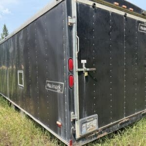 30 2 - Montana Auctions by Kevin Hill Black Haulmark cargo trailer parked in a grassy field, side and rear doors visible.