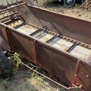 43 1 - Montana Auctions by Kevin Hill Old, rusted farming implement with metal tines, lying in dry grass beside a tractor wheel in a field.