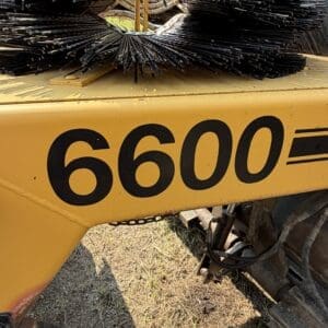5 1 - Montana Auctions by Kevin Hill Front view of a yellow industrial machine with a large rotating circular brush; the side shows the number 6600.