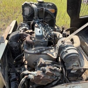 6 5 - Montana Auctions by Kevin Hill Open engine compartment of a dusty diesel engine on a utility vehicle in a grassy field outside.