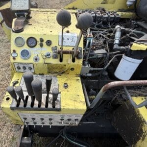 8 2 - Montana Auctions by Kevin Hill Old yellow control console with multiple levers, gauges, and tangled wires on a worn machine exterior.