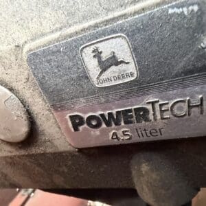 9 4 - Montana Auctions by Kevin Hill Close-up of a John Deere PowerTech 4.5 liter engine plate on a dusty surface.