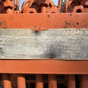 IMG_8533 - Montana Auctions by Kevin Hill Weathered metal nameplate on orange equipment displaying RAMMAX branding and model/weight information (faded, dirty).
