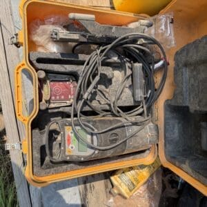 IMG_8790 - Montana Auctions by Kevin Hill Open orange tool case with tangled cords and a red control panel on a wooden surface outdoors, showing electrical testing gear.