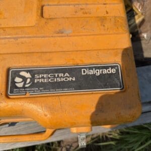 IMG_8791 - Montana Auctions by Kevin Hill Orange Dialgrade surveying instrument by Spectra Precision, showing the brand plate used for grade measurements outdoors.