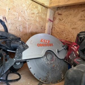 IMG_8794 - Montana Auctions by Kevin Hill Circular saw labeled C14 CoreCut resting in a cluttered wooden shed, with cords and tools nearby.