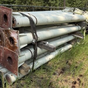 IMG_8851 - Montana Auctions by Kevin Hill Stack of rusted metal poles and red metal plates strapped together in a grassy outdoor lot.